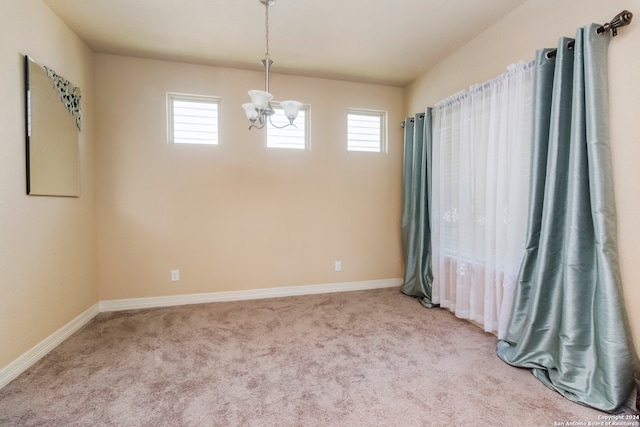 carpeted spare room with a wealth of natural light and a notable chandelier