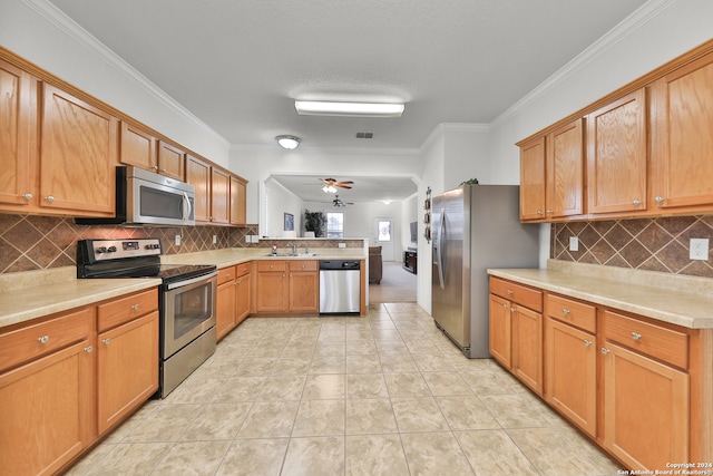 kitchen with backsplash, appliances with stainless steel finishes, light tile patterned floors, crown molding, and sink