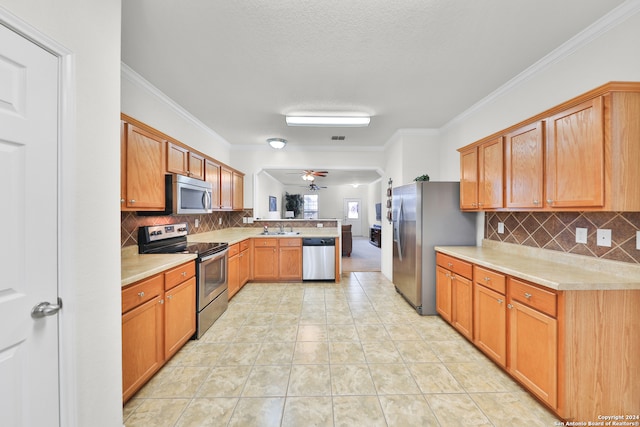 kitchen with stainless steel appliances, backsplash, sink, crown molding, and light tile patterned floors