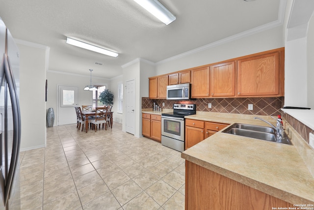 kitchen with sink, appliances with stainless steel finishes, decorative light fixtures, and backsplash