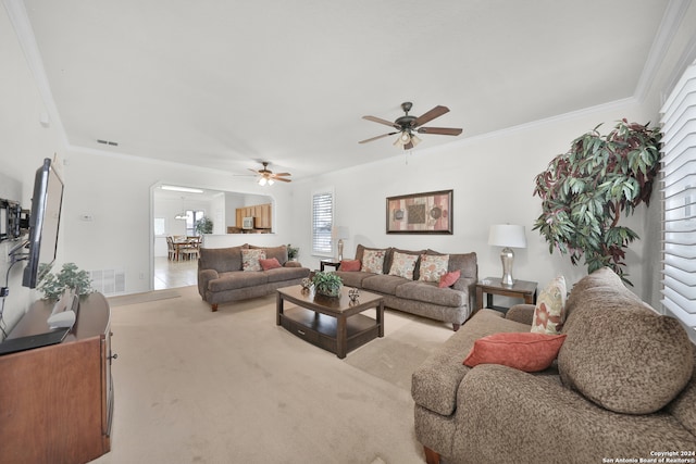 carpeted living room with ornamental molding and ceiling fan