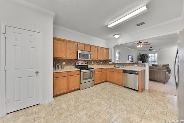 kitchen featuring decorative backsplash, sink, crown molding, light tile patterned flooring, and appliances with stainless steel finishes