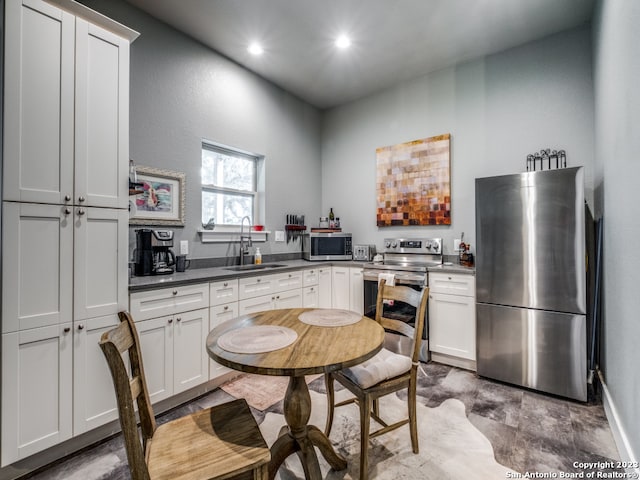 kitchen featuring appliances with stainless steel finishes, white cabinets, hardwood / wood-style flooring, and sink