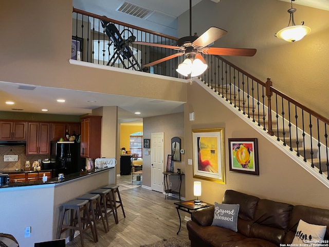 living room with a high ceiling, hardwood / wood-style flooring, and ceiling fan