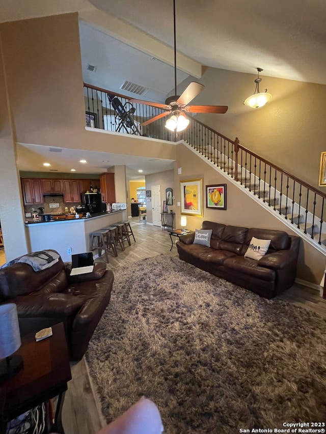 living room with ceiling fan, high vaulted ceiling, beamed ceiling, and light hardwood / wood-style floors