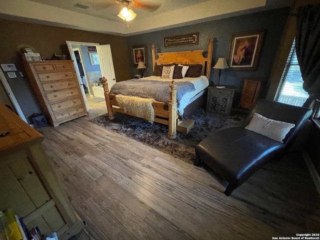 bedroom with connected bathroom, ceiling fan, and hardwood / wood-style flooring