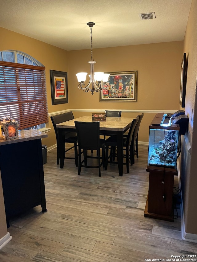 dining area featuring hardwood / wood-style flooring, a textured ceiling, and a chandelier