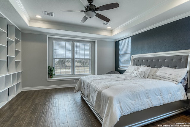 bedroom with dark wood-type flooring, crown molding, a tray ceiling, and ceiling fan