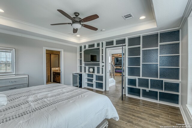 bedroom featuring hardwood / wood-style flooring, a tray ceiling, ornamental molding, ensuite bathroom, and ceiling fan