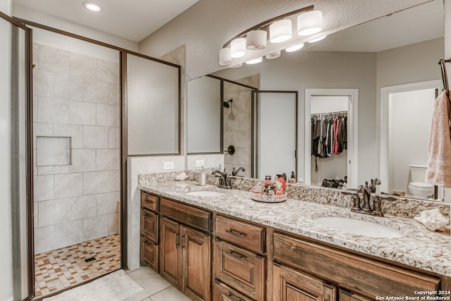 bathroom with vanity, a shower with shower door, toilet, and tile patterned floors