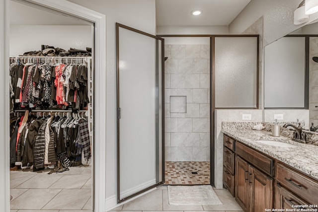 bathroom with a shower with door, vanity, and tile patterned flooring