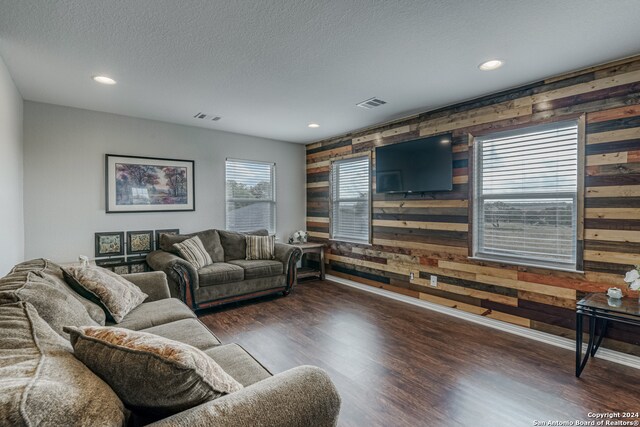 living room featuring a textured ceiling, wooden walls, and dark hardwood / wood-style flooring