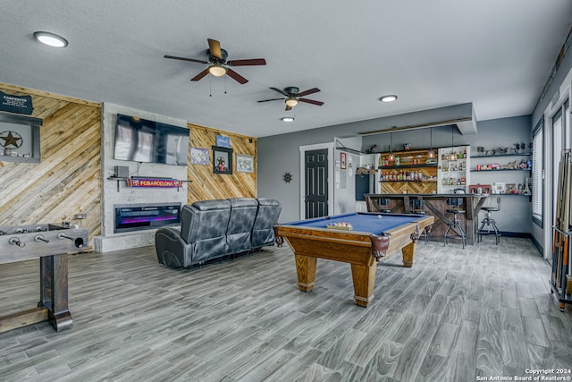 game room with pool table, hardwood / wood-style flooring, wooden walls, indoor bar, and ceiling fan