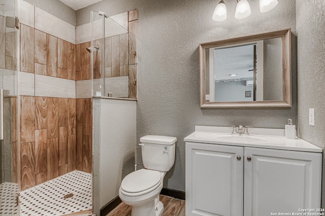 bathroom with a tile shower, hardwood / wood-style floors, toilet, and vanity