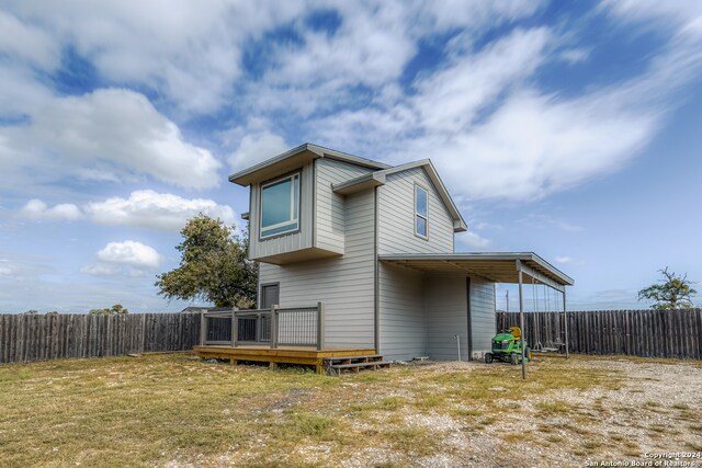 back of house featuring a deck and a lawn