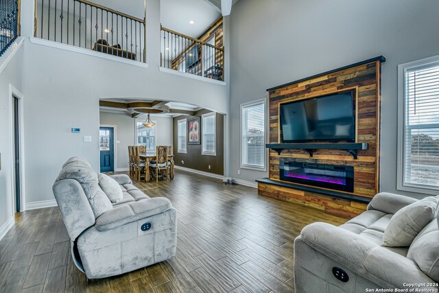 living room featuring a towering ceiling and dark wood-type flooring