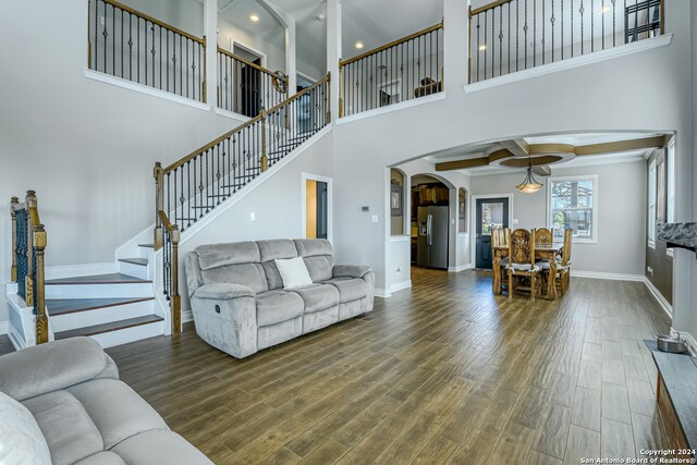 living room with beamed ceiling, dark wood-type flooring, and a towering ceiling