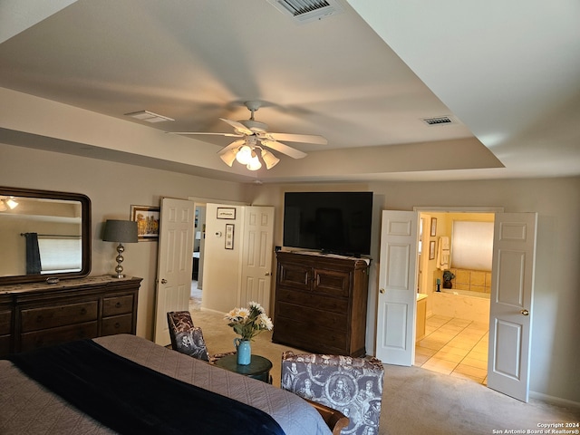 bedroom with connected bathroom, light carpet, and ceiling fan