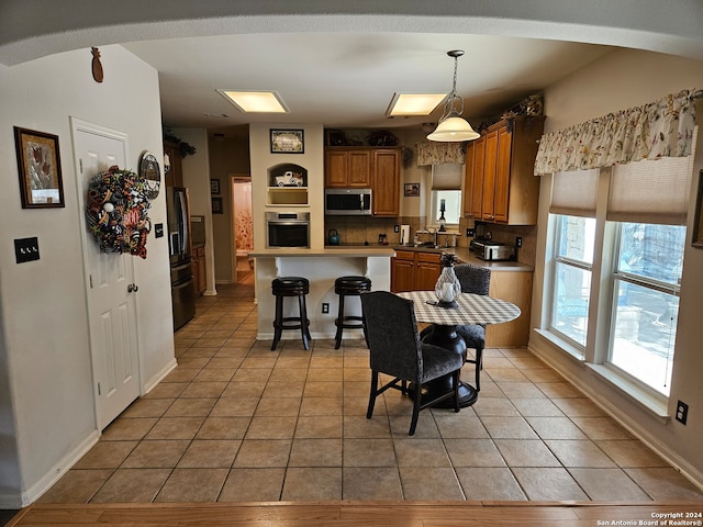 kitchen with hanging light fixtures, backsplash, appliances with stainless steel finishes, a kitchen island, and a kitchen bar