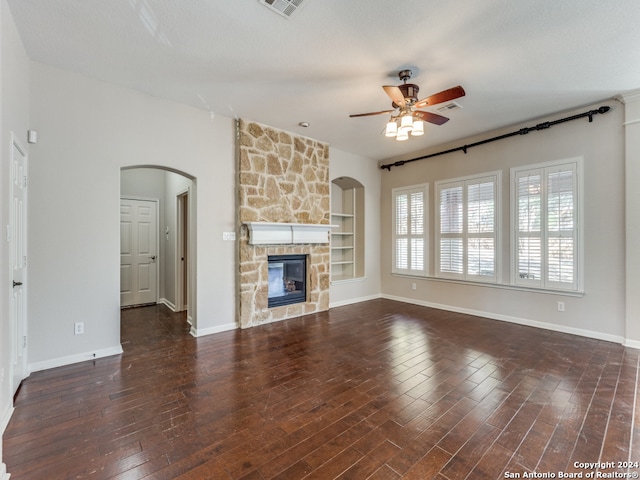 unfurnished living room with a fireplace, dark wood-type flooring, built in features, and ceiling fan