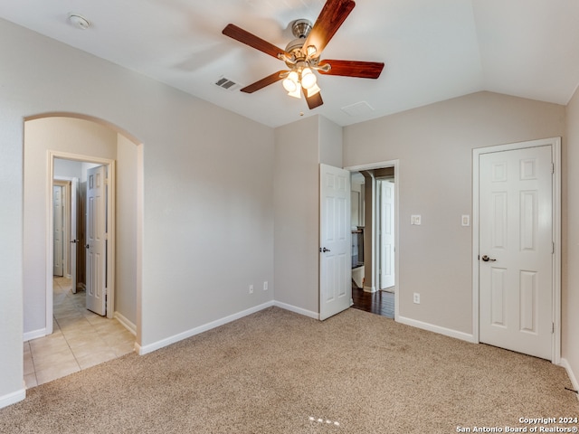 unfurnished bedroom featuring light carpet, lofted ceiling, and ceiling fan