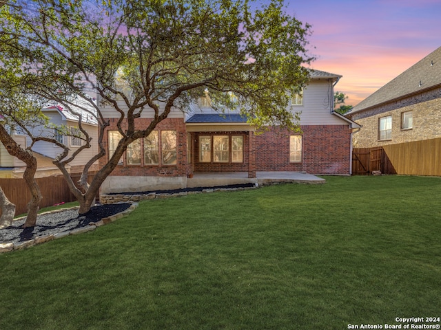 back house at dusk with a lawn