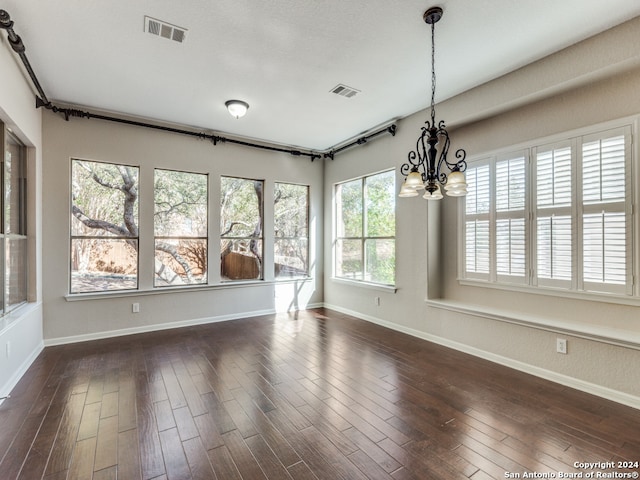 unfurnished dining area featuring dark wood-type flooring and an inviting chandelier