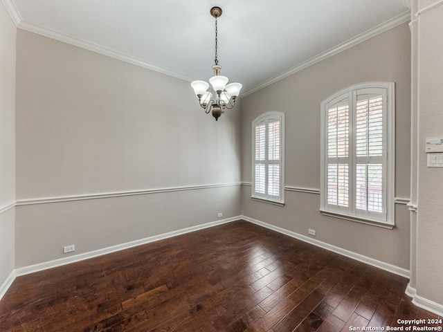 spare room with crown molding, dark wood-type flooring, and a chandelier