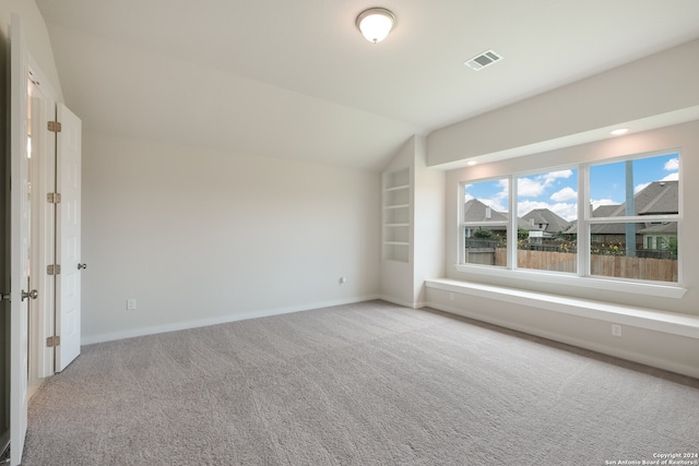 additional living space with light carpet and vaulted ceiling