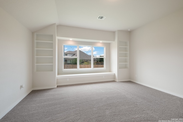 unfurnished room featuring carpet, vaulted ceiling, and built in shelves