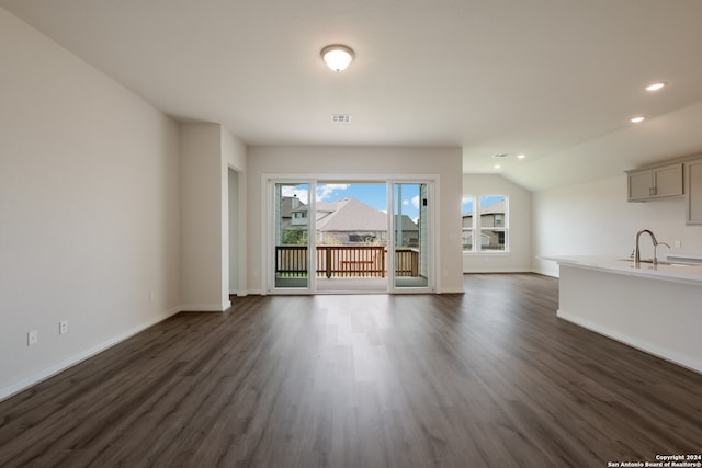 unfurnished living room with dark wood-type flooring, lofted ceiling, and sink