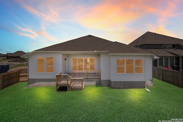 back house at dusk with a lawn