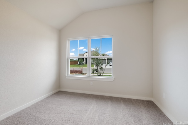 carpeted empty room featuring vaulted ceiling