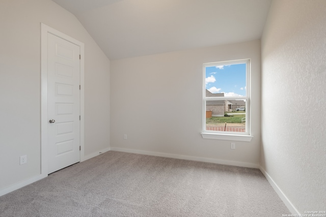 spare room with carpet and vaulted ceiling