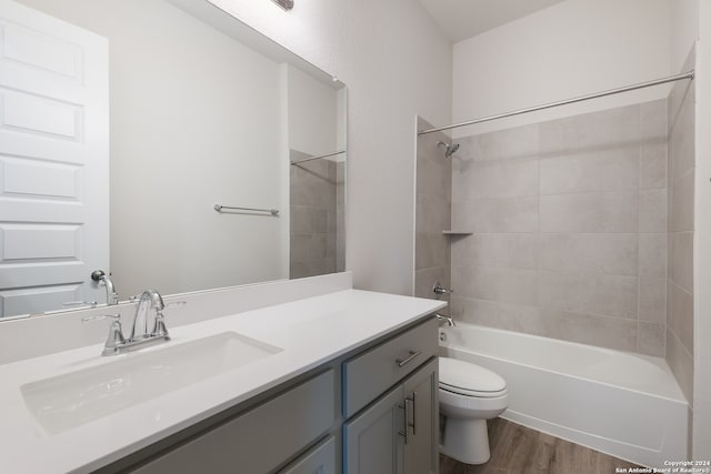 full bathroom with vanity, toilet, hardwood / wood-style flooring, and tiled shower / bath combo