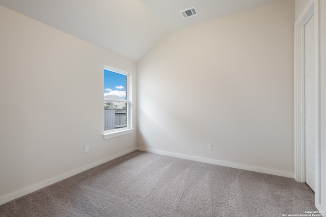 carpeted spare room with vaulted ceiling