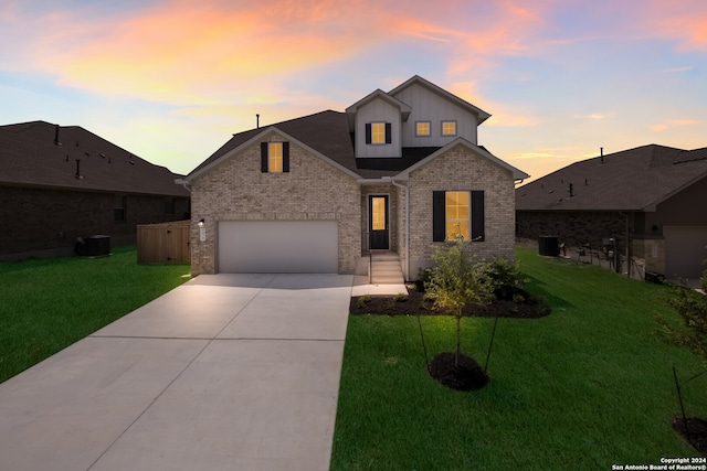 view of front facade with central air condition unit, a lawn, and a garage