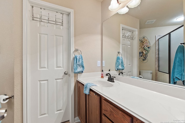 bathroom featuring toilet, a textured ceiling, walk in shower, and vanity