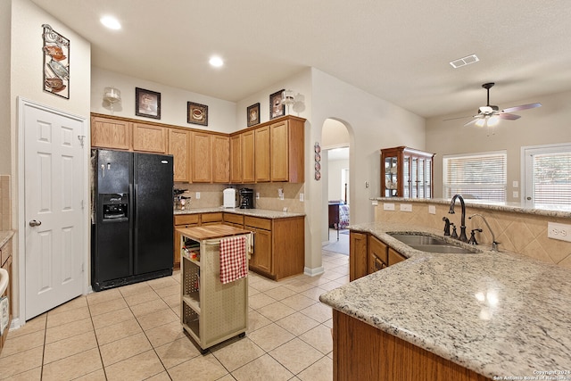 kitchen with a kitchen island, sink, light tile patterned flooring, black fridge with ice dispenser, and ceiling fan