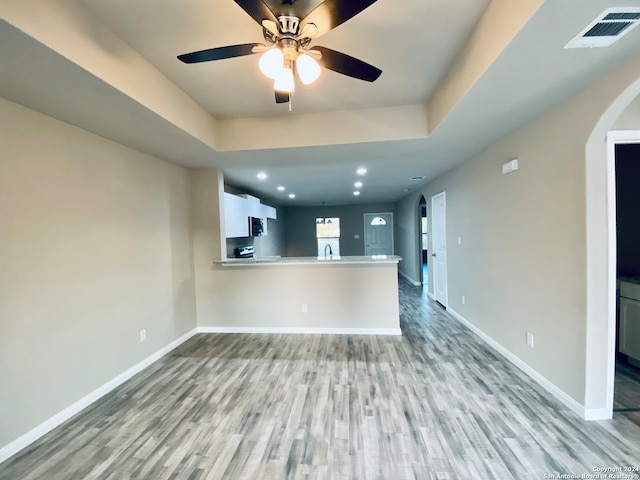 spare room featuring a tray ceiling, light hardwood / wood-style flooring, and ceiling fan