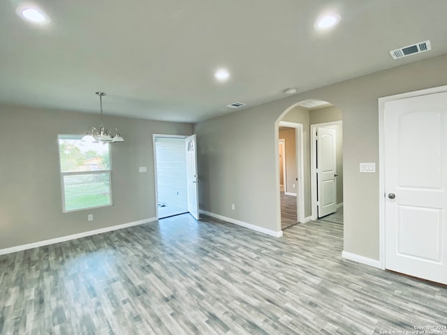 unfurnished room featuring an inviting chandelier and light hardwood / wood-style flooring