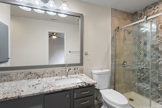 bathroom featuring vanity, toilet, a shower with door, and ceiling fan