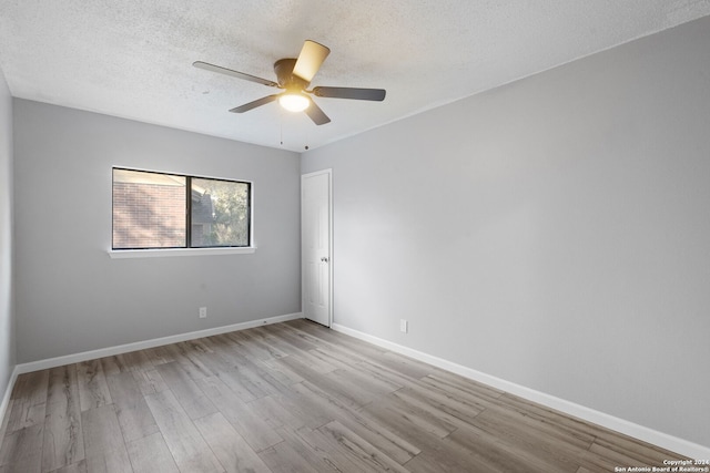 unfurnished room with a textured ceiling, light wood-type flooring, and ceiling fan