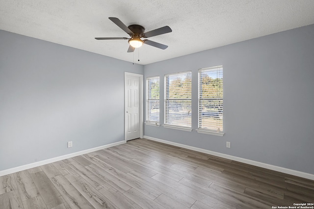 empty room with light hardwood / wood-style floors, a textured ceiling, and ceiling fan