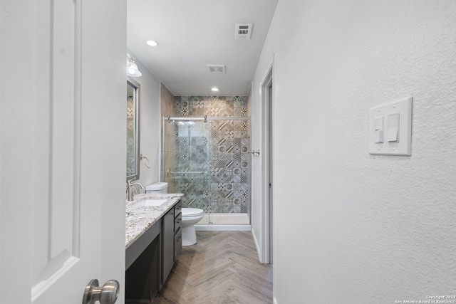 bathroom featuring vanity, toilet, an enclosed shower, and parquet floors