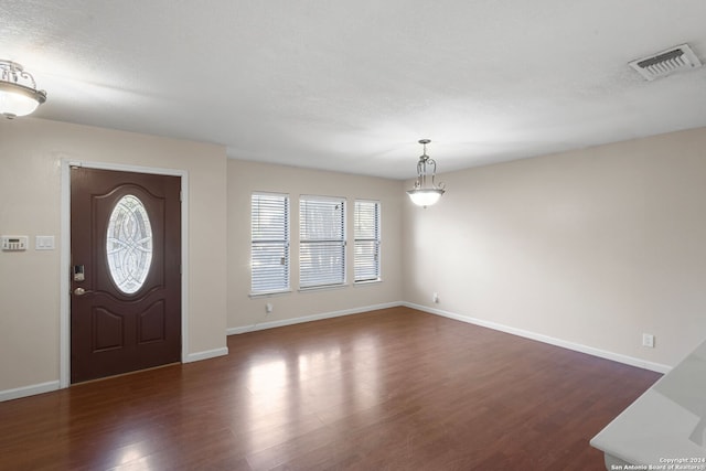 foyer entrance featuring a textured ceiling and dark wood-type flooring