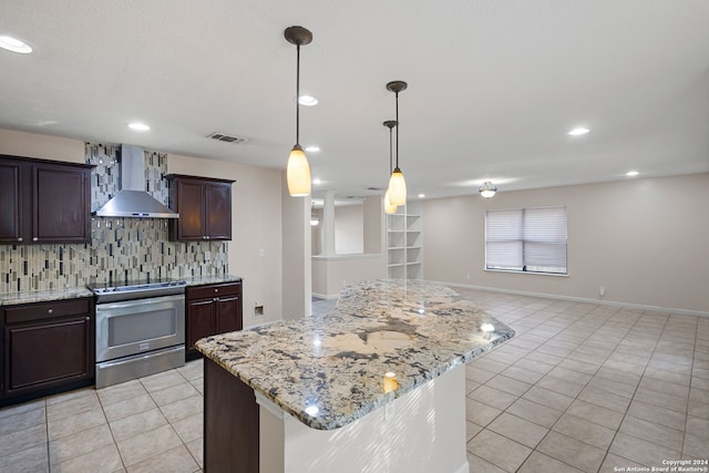 kitchen featuring wall chimney range hood, backsplash, a center island, light stone counters, and electric stove