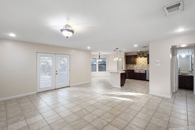 kitchen featuring a center island, light stone countertops, light tile patterned flooring, and dark brown cabinets