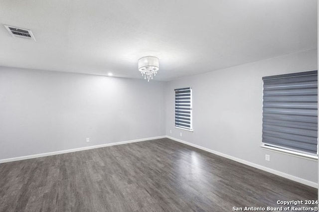 spare room with a chandelier and dark hardwood / wood-style flooring