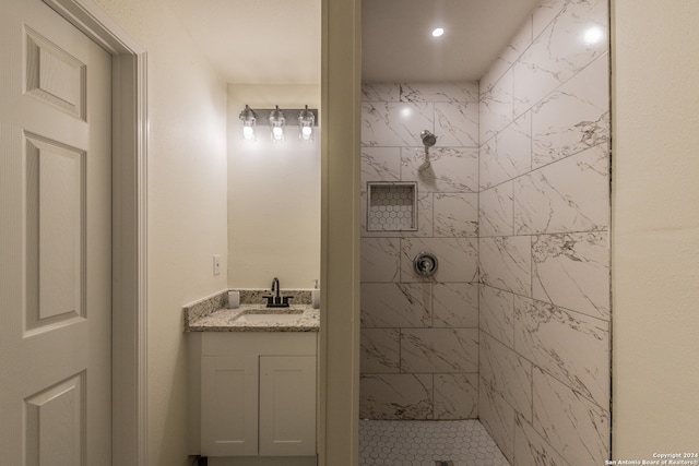 bathroom with a tile shower and vanity